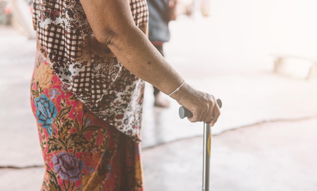 Anciana sosteniendo un problema de salud de bastón trípode y concepto médico