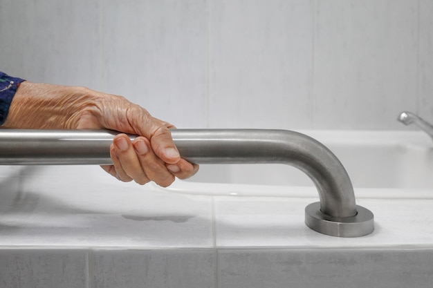 Anciana sujetando el pasamanos en el baño.