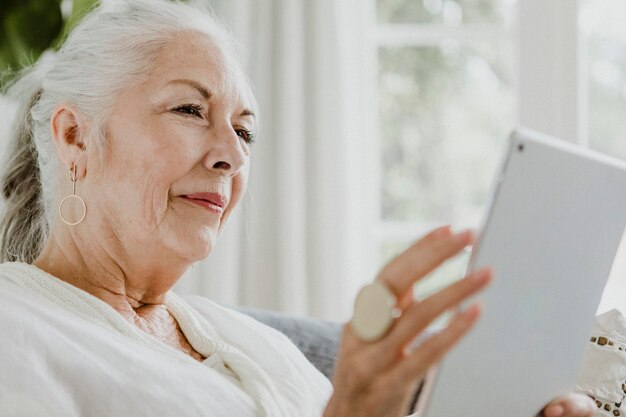 Anciana con una tableta en un sofá