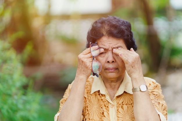 Anciana tailandesa masajea las cuencas de los ojos debido al dolor ocular después de usar demasiados ojos