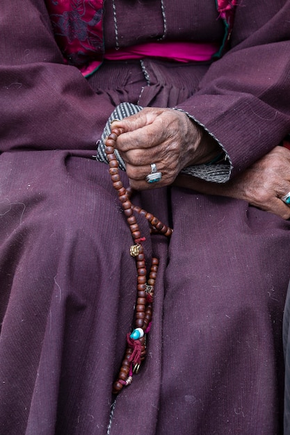 Anciana tibetana sosteniendo un rosario budista en el monasterio de Hemis, Ladakh, India. Mano y rosario