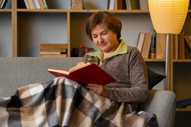 Foto anciana de tiro medio leyendo en casa