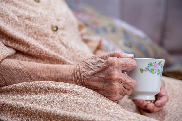 Anciana tomando café con una sonrisa en su rostro