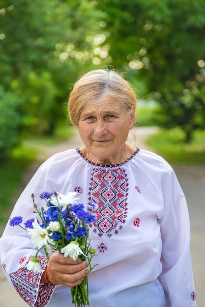 Una anciana ucraniana en una camisa bordada con un ramo de flores Enfoque selectivo