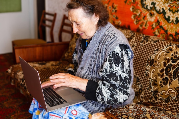 Anciana usando una computadora portátil en casa