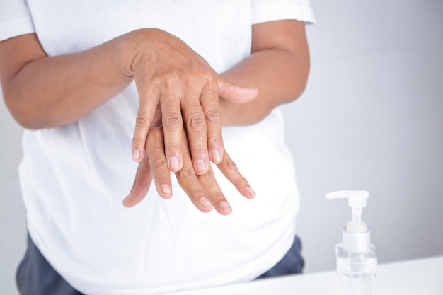 Anciana vestida de blanco lavarse las manos con gel de alcohol