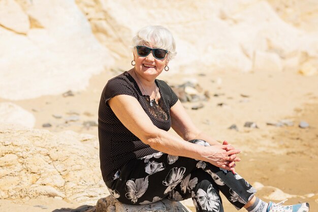 Anciana vestida de negro sentada en una roca cerca del mar