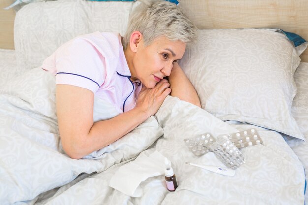 anciana yace en una cama con pastillas