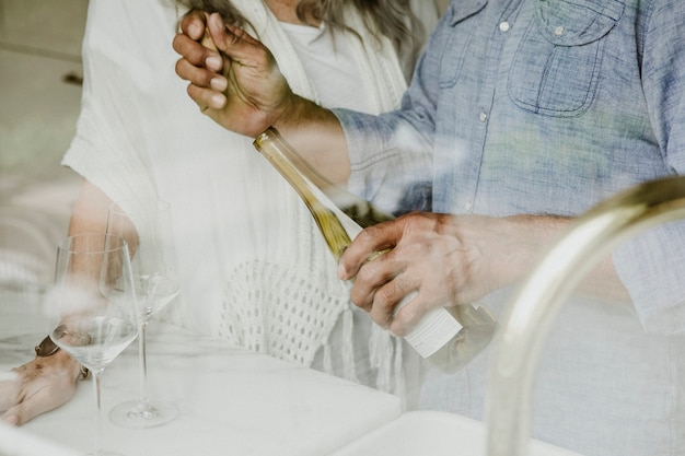 Anciano abriendo una botella de vino blanco