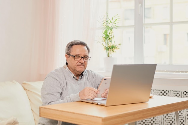 Un anciano alegre tiene una conversación telefónica en casa