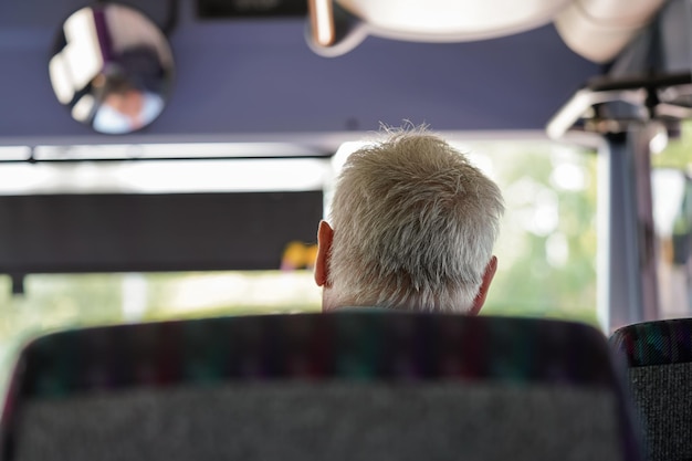 Anciano anciano viajando en autocar, vista desde atrás de los detalles solo a su cabeza de pelo gris