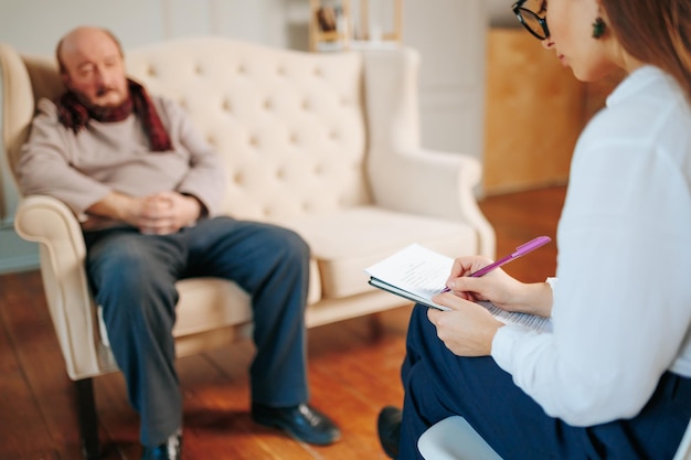 Anciano angustiado hablando con un psicólogo durante la sesión de terapia en el interior Ayudar a apoyar el ptsd