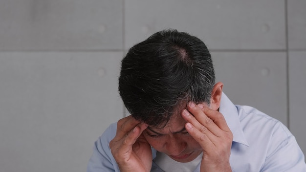 Anciano asiático con dolor de cabeza por migraña El hombre se siente estresado y preocupado por problemas de salud