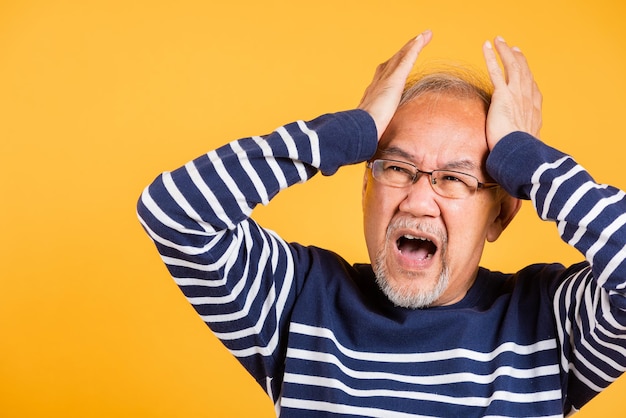 Anciano asiático manos sosteniendo la cabeza y cerrar las orejas que sufren de dolor de cabeza