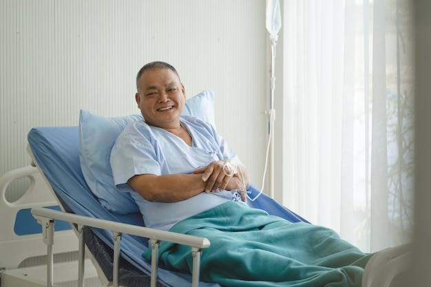 Anciano asiático sonrió en la cama en el hospital