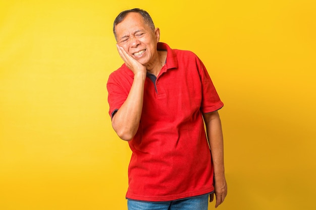 El anciano asiático sufre de dolor de muelas aislado de fondo amarillo