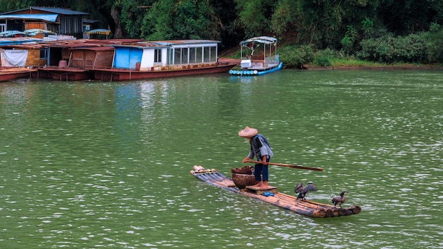 El anciano en una balsa cruza el río Li conocido así como el río Lijiang