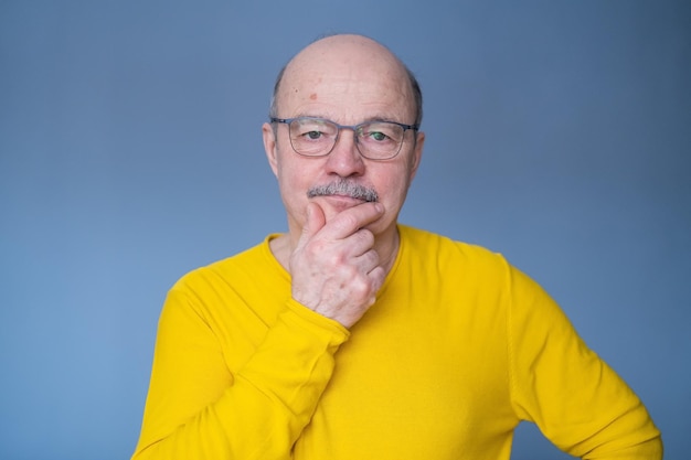 Un anciano calvo con gafas pensando en intentar tomar una decisión. foto de estudio