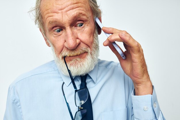 Anciano en una camisa con corbata con un fondo claro de tecnología telefónica