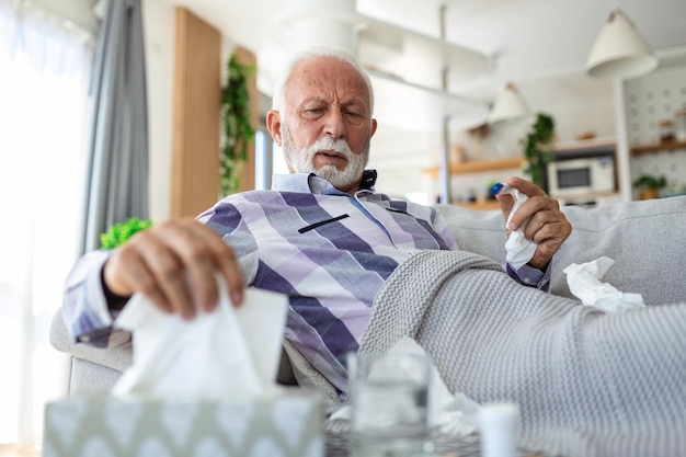 Foto un anciano enfermo revisando su temperatura que sufre de gripe estacional o resfriado acostado en un sofá que sufre de gripe estacional o resfriado los ancianos enfermos se sienten enfermos con influenza en casa