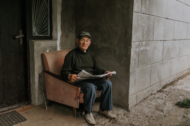 Anciano de gafas con cabello gris leyendo un periódico