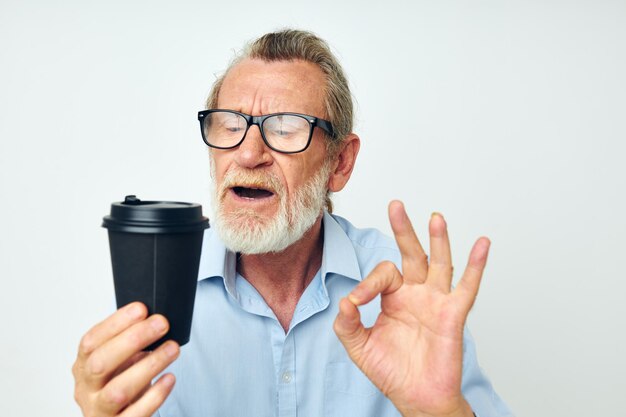 El anciano gesticula con las manos un vaso de bebida de fondo aislado