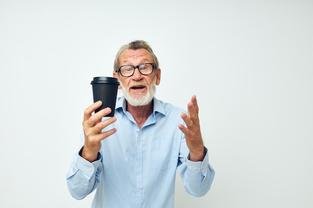 El anciano gesticula con las manos un vaso de bebida de fondo aislado