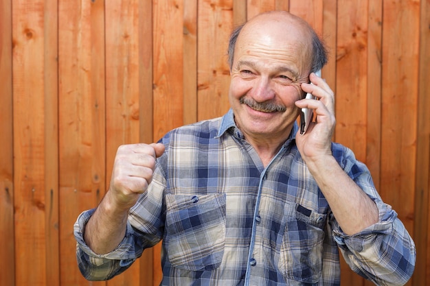 Anciano hablando por teléfono y recibe un mensaje sobre las buenas noticias Joy ganancias o premio