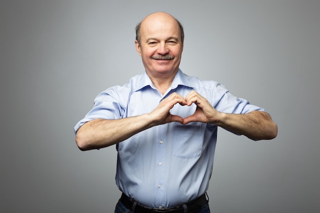 Anciano haciendo de las manos el corazón Haciendo obras de caridad cuidando la salud o estando enamorado