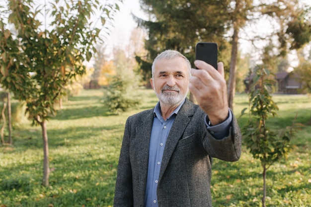 Anciano haciendo un video en el teléfono inteligente afuera