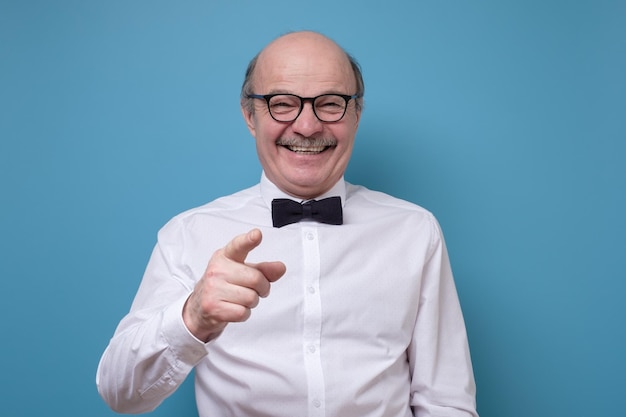 Un anciano hispano con gafas apuntándote con el dedo