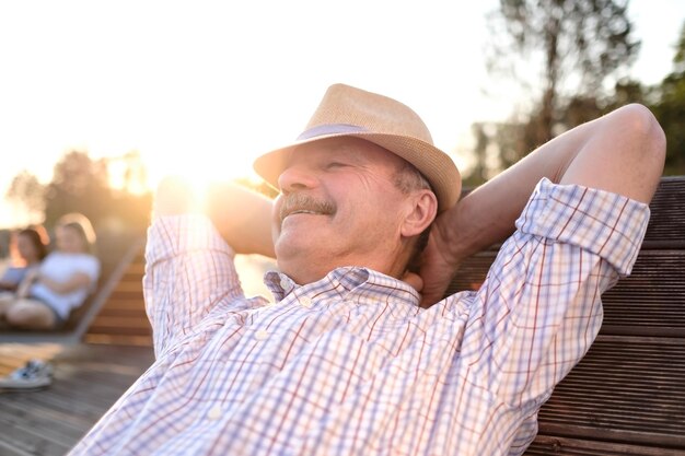 El anciano hispano se sienta en un banco sonriendo disfrutando del día soleado de verano