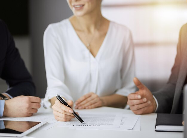 Anciano hombre de negocios y grupo de empresarios discutiendo contrato en oficina soleada, primer plano.