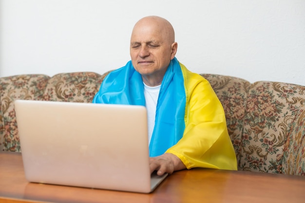 Anciano con laptop y bandera de ucrania