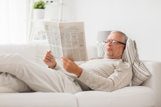 Foto un anciano leyendo el periódico en casa.