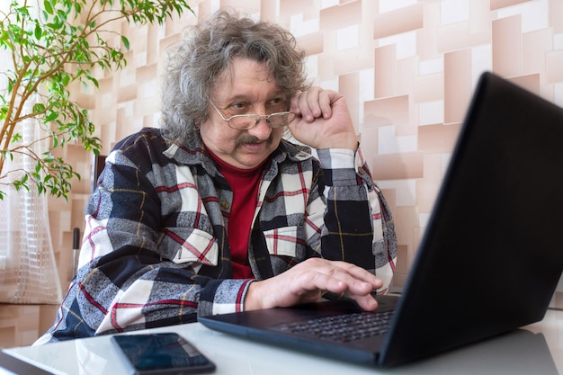 Un anciano con mala vista trabajando en la computadora