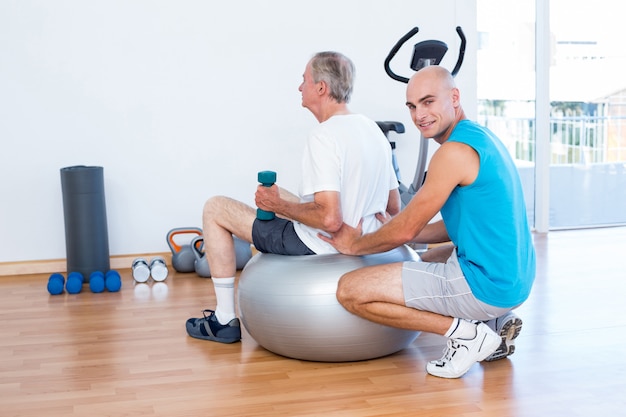 Foto anciano con masaje de espalda en la pelota de ejercicios