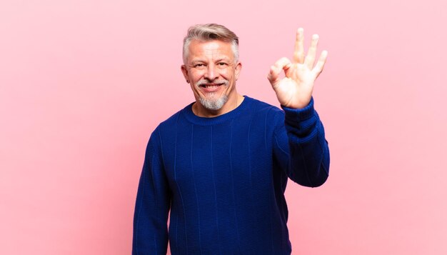 Anciano mayor que se siente feliz, relajado y satisfecho, mostrando aprobación con gesto bien, sonriendo