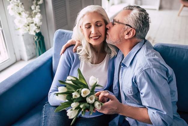 El anciano y una mujer con flores besándose.