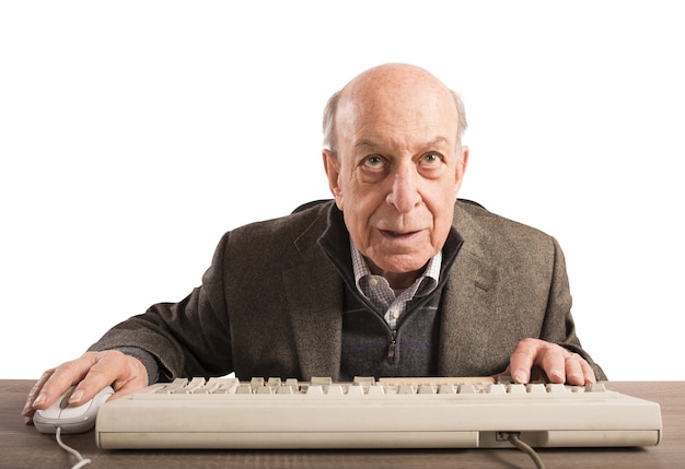 Anciano nerd trabaja con su teclado vintage