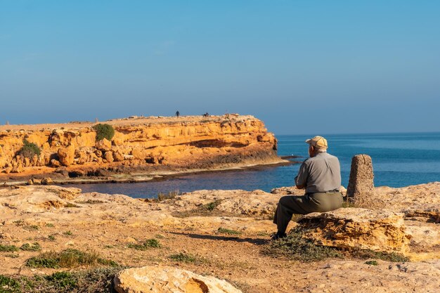 Anciano pensativo sentado en la costa junto al mar Señor tradicional de la cultura española