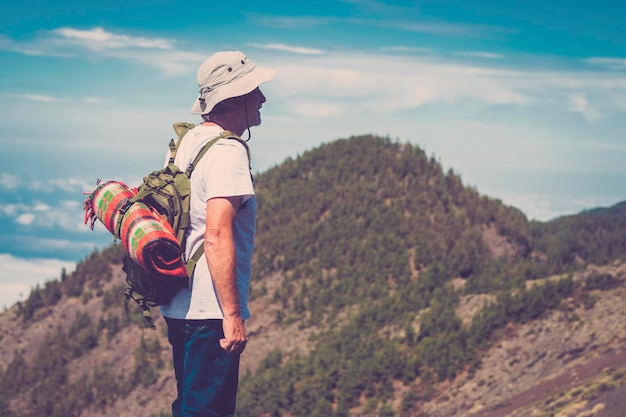 Un anciano de pie contra un hermoso paisaje en la cima de la montaña con mochila Estilo de vida de jubilación alternativo personas de edad madura disfrutando de la libertad y la actividad saludable del viaje de ocio al aire libre