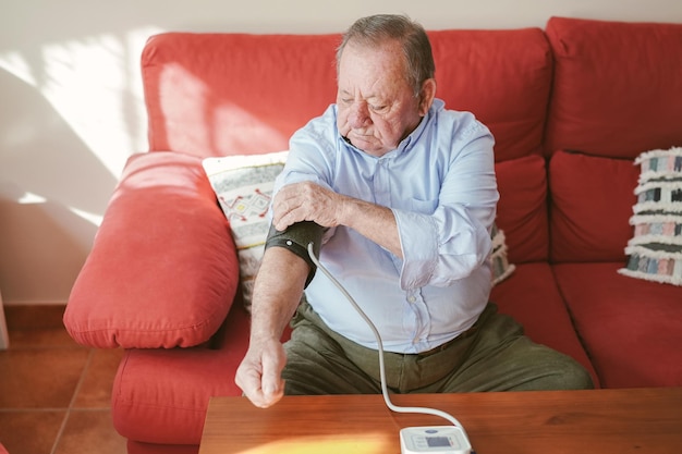 Anciano pone el manguito del monitor de presión arterial en su brazo derecho Salud