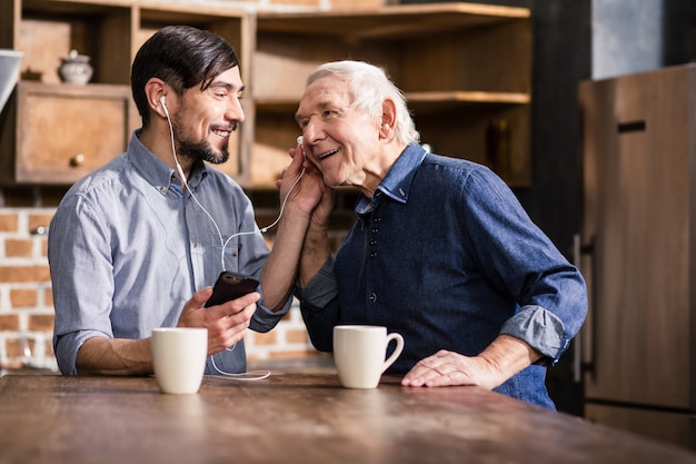 Anciano positivo hablando por teléfono mientras está sentado con su hijo