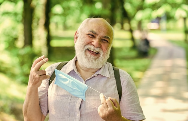 El anciano se quita la máscara médica, el anciano camina en la vida del parque durante el bloqueo del coronavirus, disfruta de la belleza, el miedo a la estrategia de enfermedad en la lucha contra la prohibición del virus de visitar lugares públicos