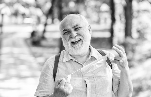 Foto el anciano se quita la máscara médica, el anciano camina en la vida del parque durante el bloqueo del coronavirus, disfruta de la belleza, el miedo a la estrategia de enfermedad en la lucha contra la prohibición del virus de visitar lugares públicos