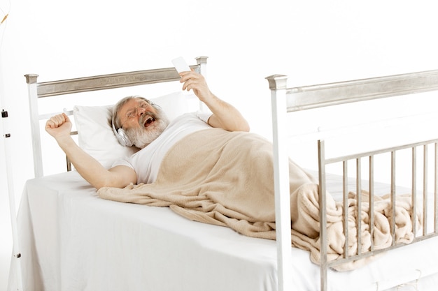 Anciano recuperándose en una cama de hospital aislado en blanco