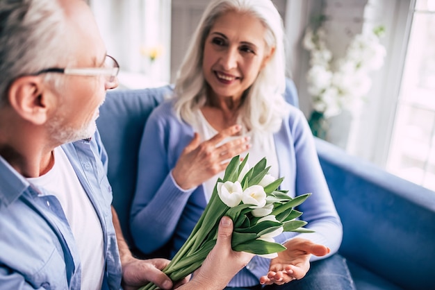 El anciano regalando flores a una anciana.