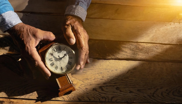 Un anciano con un reloj antiguo en las manos observa cómo pasa el tiempo.