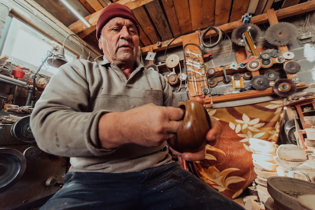 Un anciano sentado en el taller y untando utensilios de madera con aceite de linaza